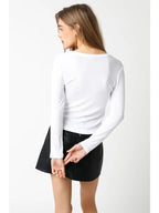 Woman wearing a white ribbed long sleeve top paired with a black skirt, viewed from behind in women's clothing style.