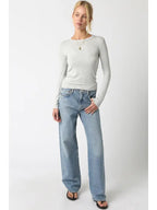 Woman wearing a light gray ribbed long sleeve top paired with light blue wide-leg jeans and black sandals.