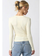 Woman wearing a fitted cream ribbed long sleeve top paired with light blue jeans from the back view.
