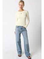 Woman wearing a cream ribbed long sleeve top paired with light blue wide-leg jeans and black sandals