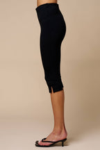 Side view of women's black knit capri pants with small side slits worn with black heeled sandals