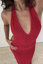 Close-up of woman wearing red knit halter dress with textured pattern, deep neckline, and open back style.