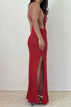 Woman wearing a red knit halter maxi dress with side slit and open back in a textured fabric, styled with heels.