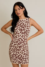 Woman wearing sleeveless fitted knit mini dress with brown leopard print pattern against beige background