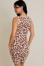Woman wearing a sleeveless leopard print knit mini dress standing against a beige background