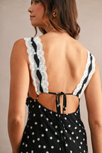 Woman wearing black polkadot maxi dress with white lace straps and an open back tied with a bow