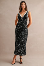 Woman wearing a black maxi dress with white polkadots and lace trim, styled as women's clothing fashion piece.