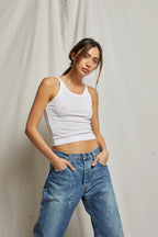 Woman wearing a fitted white tank top paired with relaxed blue denim jeans in a casual women's clothing style
