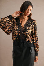 Woman wearing a leopard print blouse with black lace trim and long puff sleeves paired with a black skirt.
