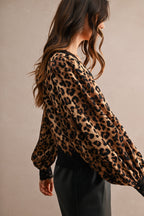 Woman wearing a leopard print blouse with lace trim on cuffs and hem, paired with black pants in a stylish look