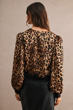 Woman wearing a leopard print blouse with lace trim detail on cuffs and hem, paired with a black skirt.