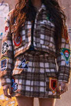 Woman wearing a brown and white plaid shacket with various colorful patches and a matching skirt in women's clothing style