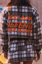 Woman wearing brown and white plaid shacket with bold orange text on the back, styled as women's clothing outerwear.