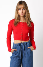 Woman wearing a cropped red long sleeve button-up sweater paired with high-waisted blue pants in women's clothing.