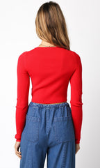Woman wearing a fitted red long-sleeve cropped sweater paired with high-waisted blue denim pants viewed from behind
