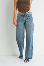 Woman wearing casual low rise baggy blue denim jeans paired with a brown sleeveless top and black heels.