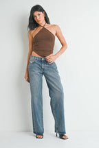 Woman wearing relaxed fit low rise baggy jeans and brown halter top, posing against white background