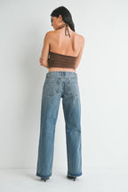Women’s relaxed fit low rise baggy jeans styled with a brown halter crop top against a white background