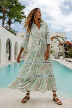 Woman wearing a flowy floral maxi dress with lace details standing near a pool in women's clothing style.