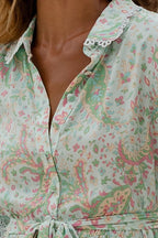 Close-up of a women's blouse with pastel floral paisley pattern and lace-trimmed collar in soft fabric.