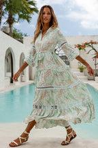 Woman wearing a flowing pastel floral maxi dress with lace details and puffed sleeves near a pool outdoors
