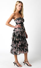 Woman wearing a strapless, tiered midi dress with floral print in a pleated fabric, styled with black heels