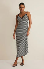 Woman wearing a black and white striped midi dress with spaghetti straps, accessorized with simple jewelry and sandals