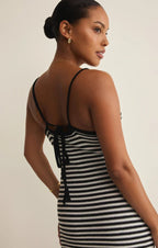 Woman wearing a fitted black and white striped midi dress with thin straps and a back tie detail in women's clothing.