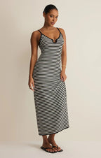 Woman wearing a black and white striped midi dress with thin straps, posing against a neutral background.