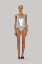 Woman wearing a sleeveless silver metallic bodysuit with low back and silver hardware, styled for women's clothing.