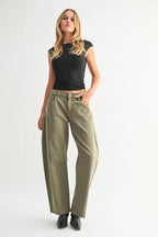 Woman wearing olive green mid-rise wide-leg jeans with front pockets and a fitted black sleeveless top in studio.