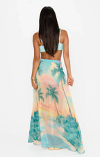 Woman wearing a pastel tropical print maxi skirt paired with a light blue crop top in women's clothing style
