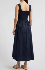 Woman wearing a sleeveless navy midi dress with a ribbed bodice and a flowing skirt, shown from the back.