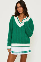 Woman wearing a green cable knit V-neck sweater with white trim and an oversized fit in women's clothing.