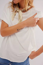 Woman wearing a white boxy tee and patterned scarf, showcasing casual women's clothing style with rolled sleeves.