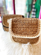 Close-up of a woven crossbody bag with beige vegan leather details on a soft white surface.
