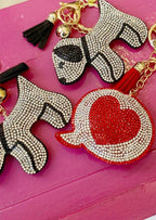 Sparkling rhinestone dog and heart keychains with tassels on vibrant pink background for women's fashion accessories