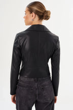 Woman wearing a fitted black leather moto jacket shown from the back, paired with dark denim jeans.