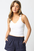 Young woman wearing a white sleeveless tank top and navy blue high-waisted casual shorts in a fashion photo.