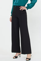 Woman wearing black wide-leg seamed pants paired with a teal long-sleeve blouse and black heels.