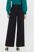 Woman wearing black wide-leg ponte seamed pants paired with a teal long-sleeve blouse and black heels