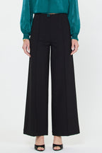 Woman wearing black wide-leg pants with front seams paired with teal long sleeve blouse and black open-toe heels