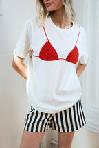Woman wearing white tee with red bikini graphic and black and white striped shorts in casual women's clothing style