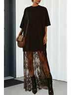 Woman wearing a black dress with lace maxi sheer skirt and black ankle boots, holding a brown shoulder bag