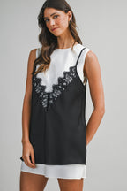 Woman wearing sleeveless black lace overlay top over white sleeveless dress in women's clothing fashion.