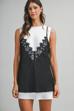 Woman wearing black lace overlay mini dress over white sleeveless underdress in women's clothing style