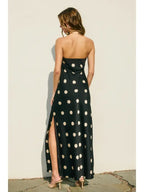 Woman wearing a black polkadot strapless maxi dress with side slit, shown from the back in women's clothing style