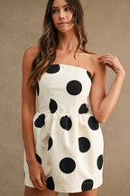 Woman wearing strapless cream mini dress with large black polkadots in casual women's clothing style