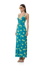 Woman wearing a teal maxi dress with green cherry print, accessorized with sunglasses and gold jewelry in women's clothing style