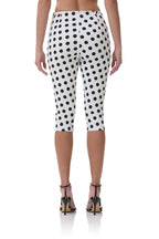 Woman wearing white capri pants with black polka dots, shown from the back in high-heeled sandals